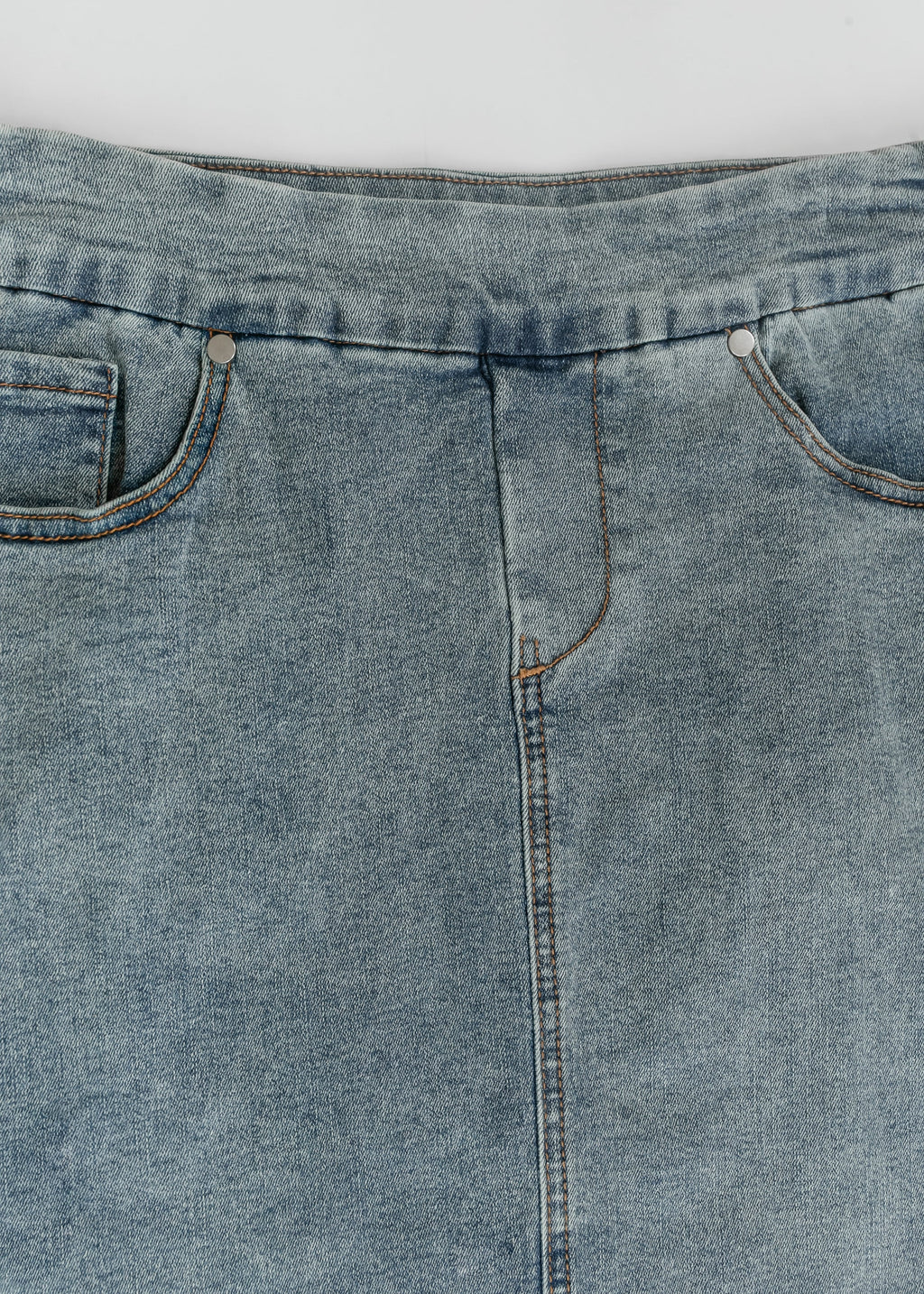 Front waistband and center seam of light blue denim midi skirt with metal button