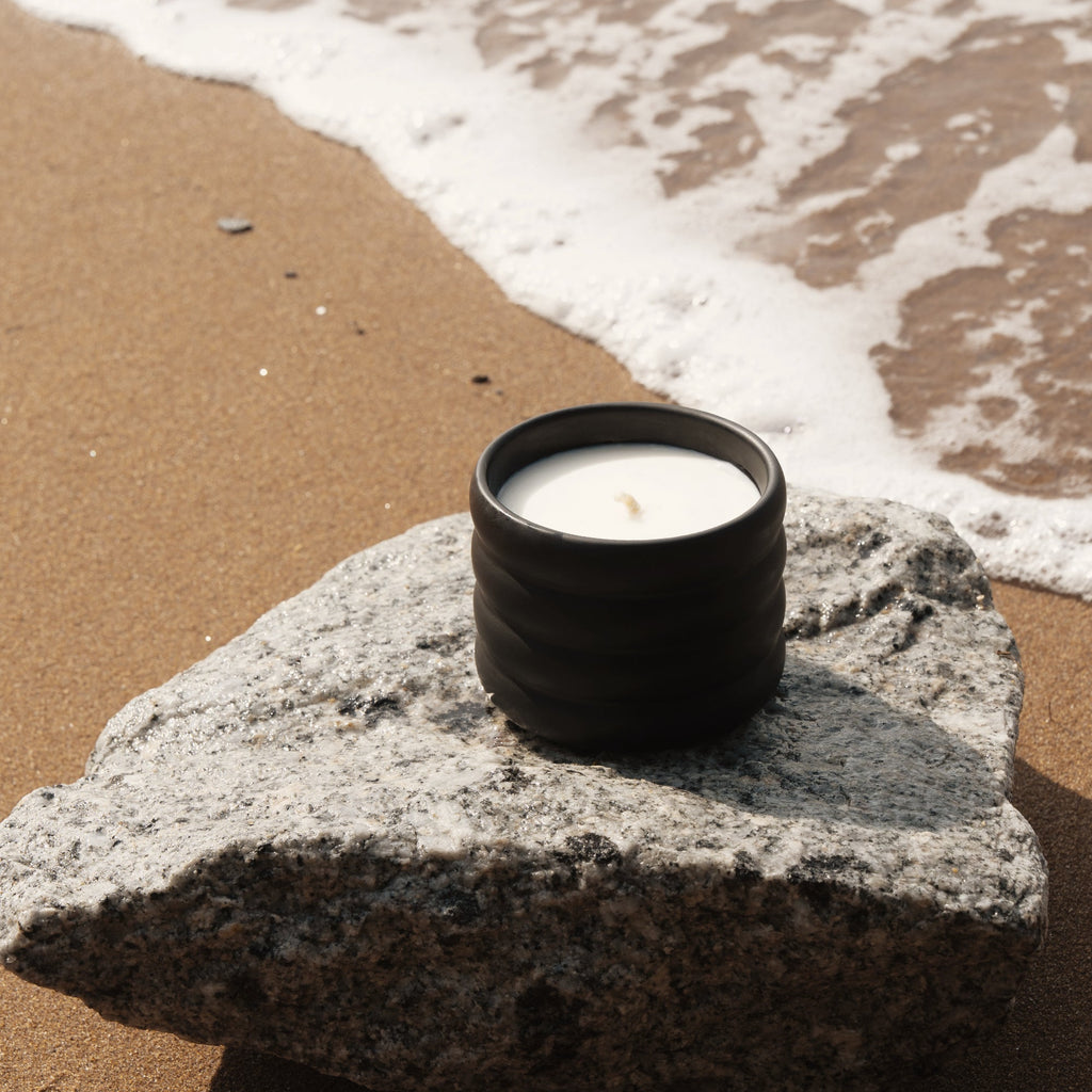 Small black ridged ceramic soy wax candle with lit wick