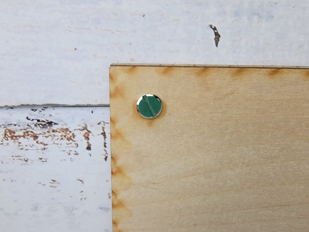 Tan picture frame corner with green circular knob and mounting hardware