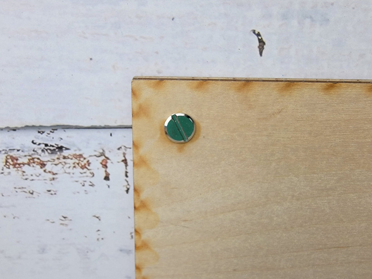 Tan picture frame corner with green circular knob and mounting hardware