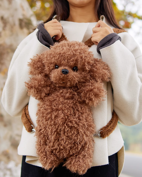 Brown plush dog backpack with curly fur and dangling paws, held in front