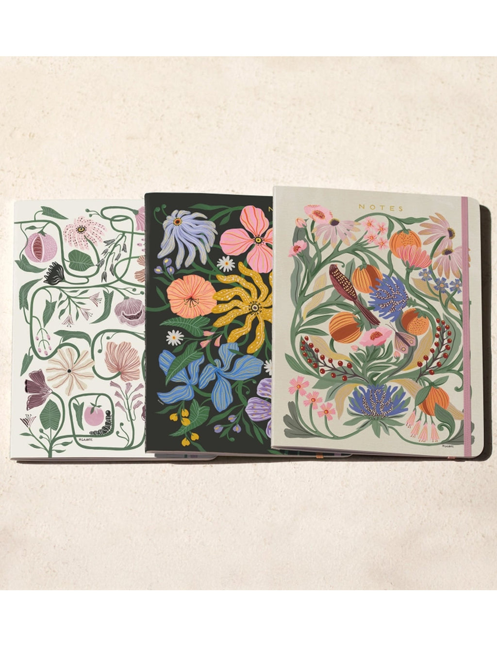 Trio notebook set open to show three patterned covers with floral and leaf designs