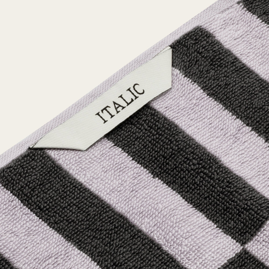 Lilac and black striped towel with woven border and label reading ITALIC.