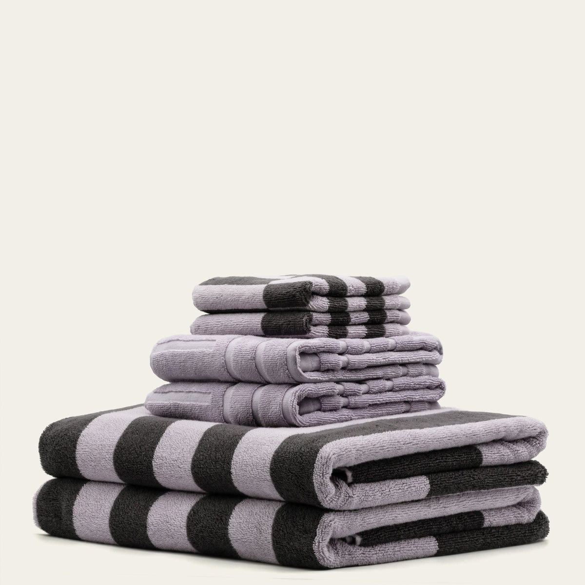 Layered lilac and charcoal striped towels with rolled folds and smooth edges.