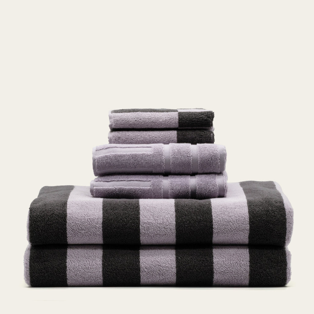 Stack of lilac and charcoal striped cotton towels, neatly folded and layered.