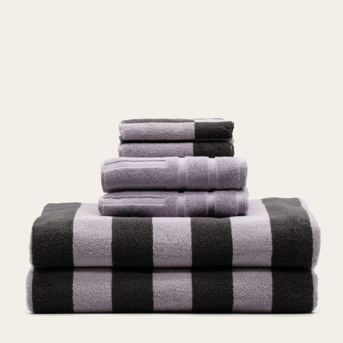 Stack of lilac and charcoal striped cotton towels, neatly folded and layered.