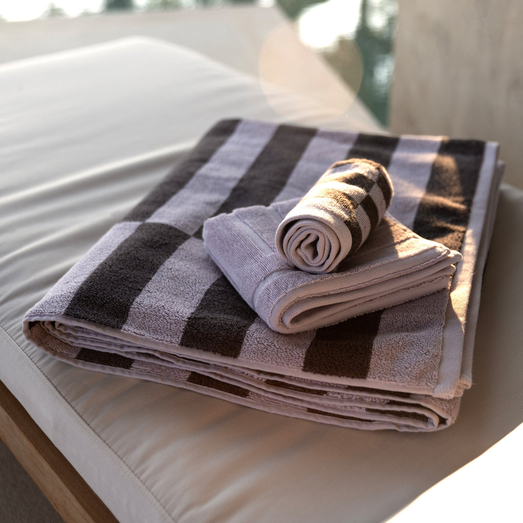 Striped cotton towels stacked neatly, black and gray with light lavender tones.