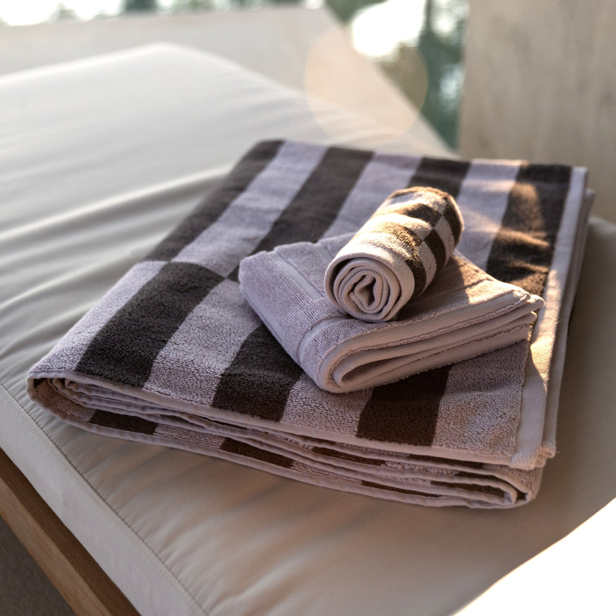 Striped cotton towels stacked neatly, black and gray with light lavender tones.