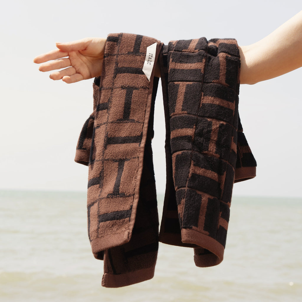Brown and black patterned cotton hand towels, folded with textured loops visible
