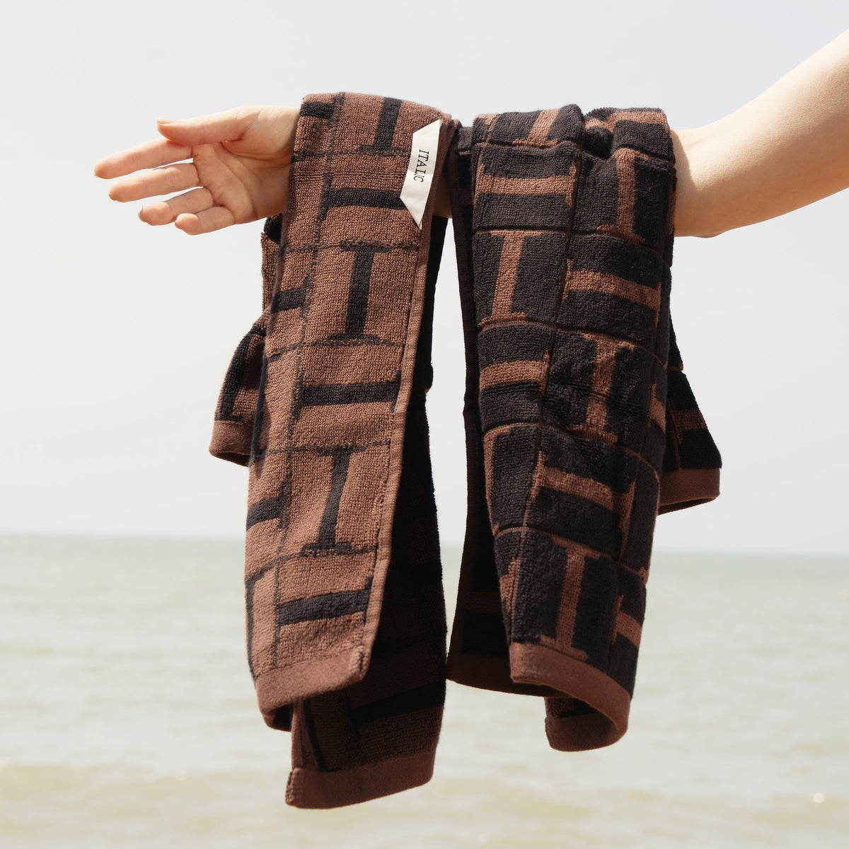 Brown and black patterned cotton hand towels, folded with textured loops visible
