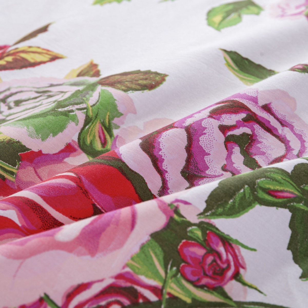 Close-up of pink rose floral fabric on a white background with green leaves
