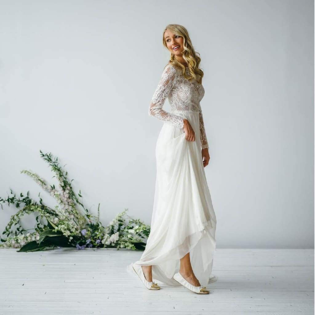 White flats with metallic toe cap and bow tie, worn with white dress hem.
