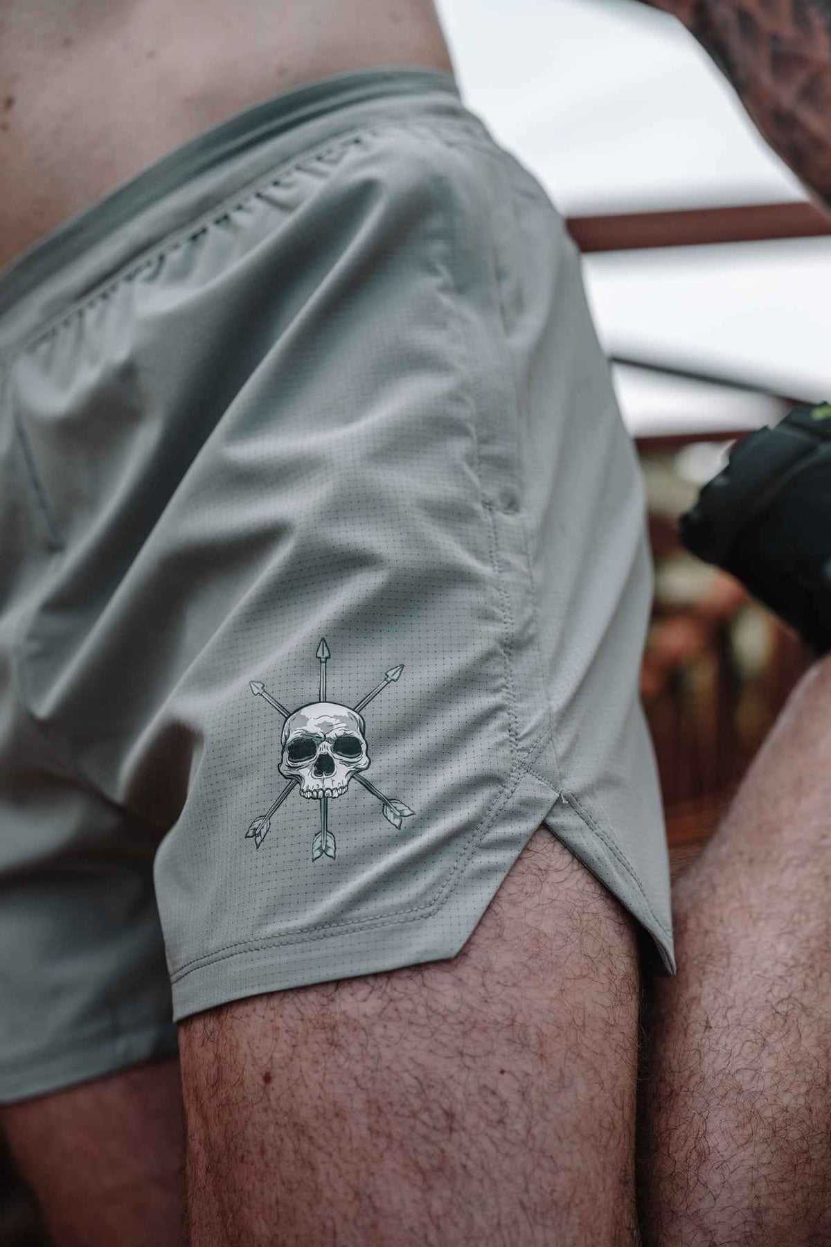 Gray shorts side close-up featuring skull-and-arrows graphic near hem.