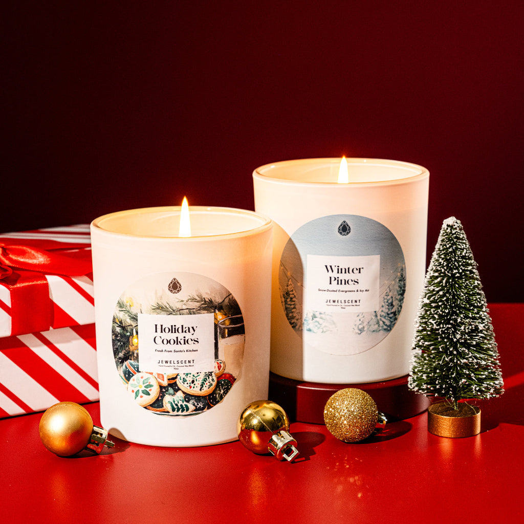 Two white candles with Winter Pines labels and burning flames