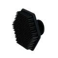 Black silicone face scrubber with dense ridged bristles and round handle base