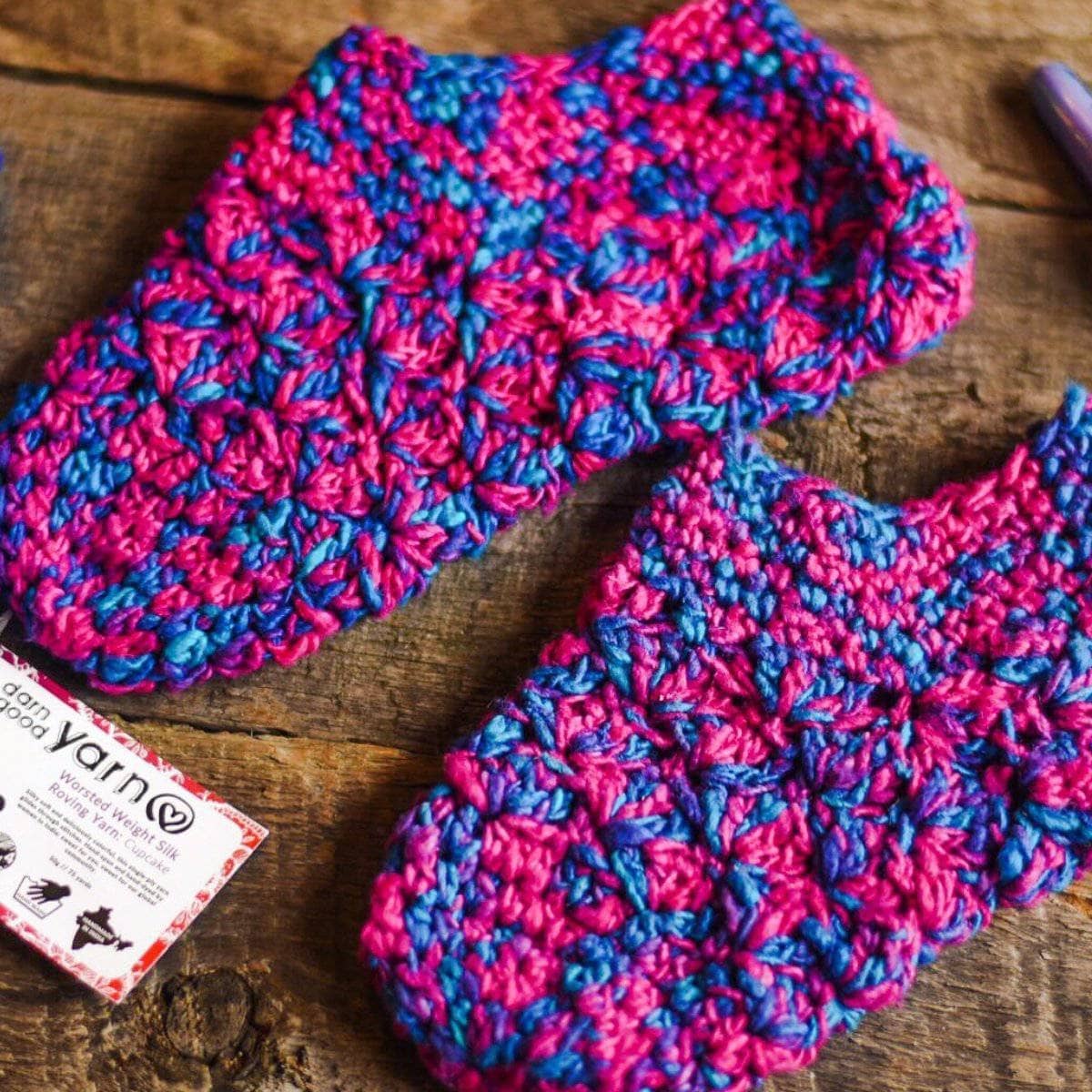 Pair of crocheted slippers in pink and blue speckled yarn, rounded toe