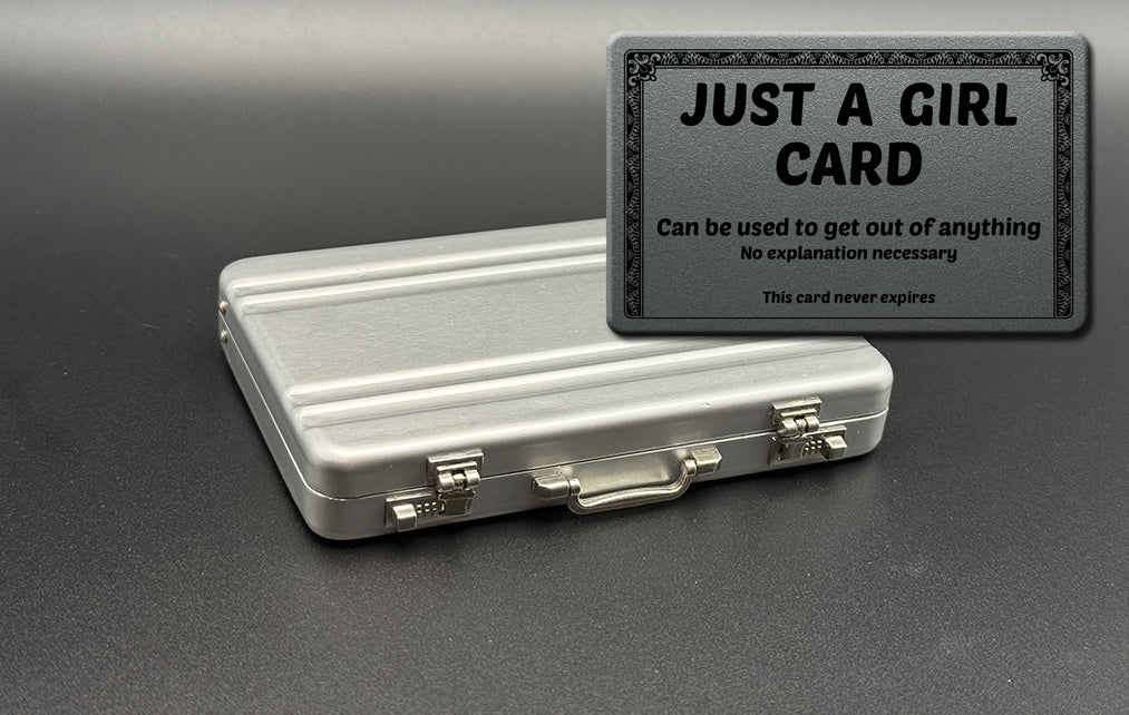 Silver mini briefcase with black “JUST A GIRL” card holder on top
