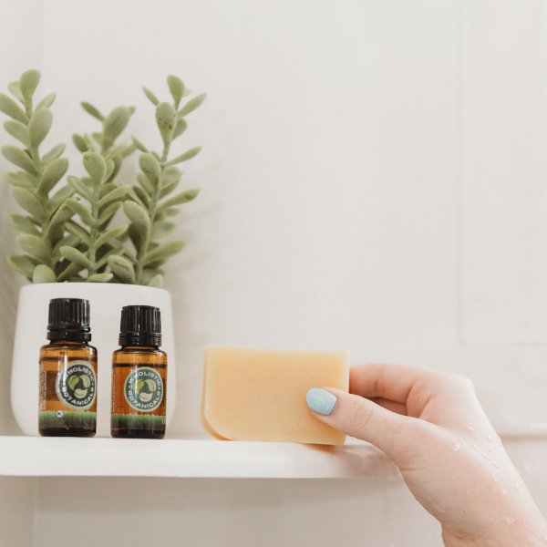 Hand holding a yellow soap bar wrapped in beige sisal soap pouch.