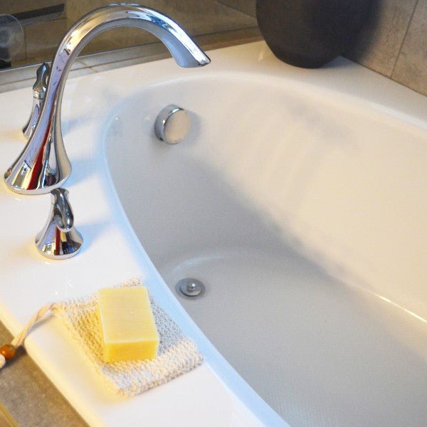 Beige sisal soap pouch with yellow soap bar next to sink drain area.