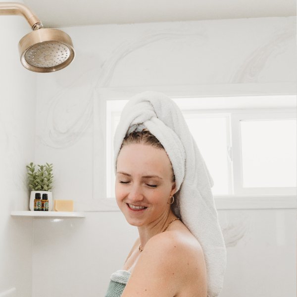 Person using a beige sisal soap pouch while bathing, tassel drawstring visible.