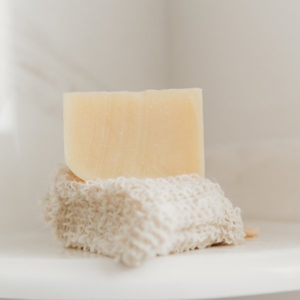 Beige sisal soap pouch with yellow soap bar resting inside.