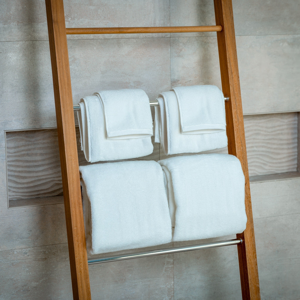 Set of light blue bath towels folded on a ladder rack, neatly stacked