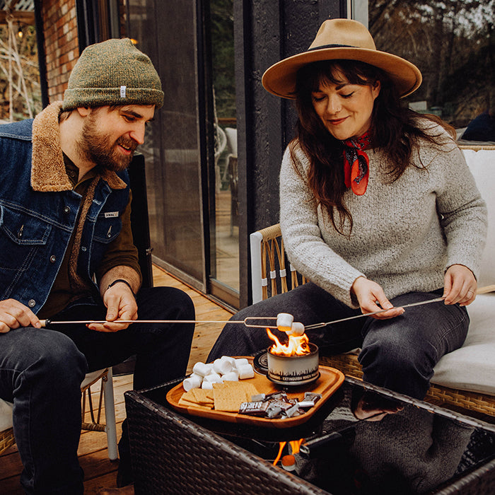 S'mores roasting sticks with marshmallow held above small campfire