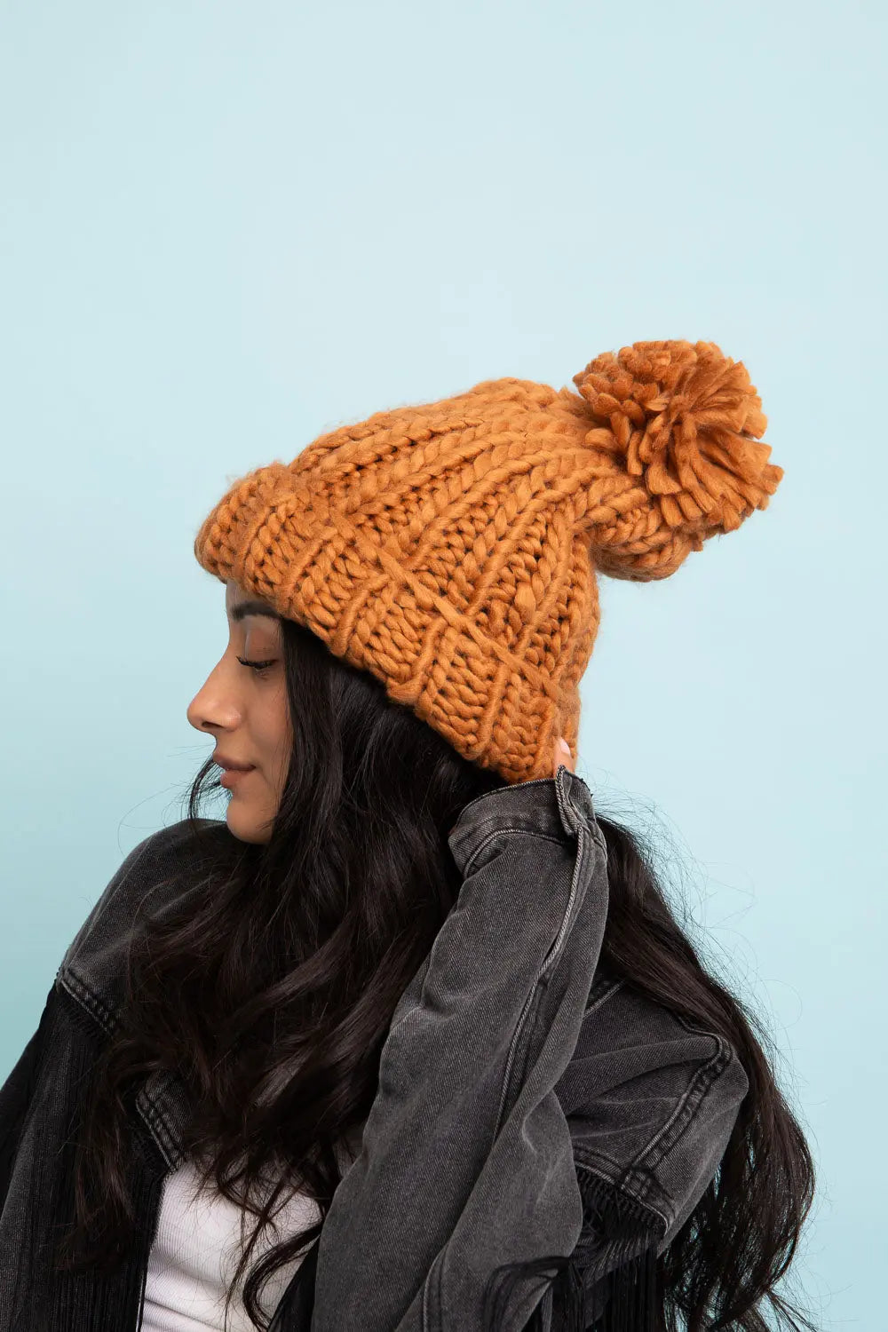 Camel cable-knit beanie with pom-pom and folded cuff, side view