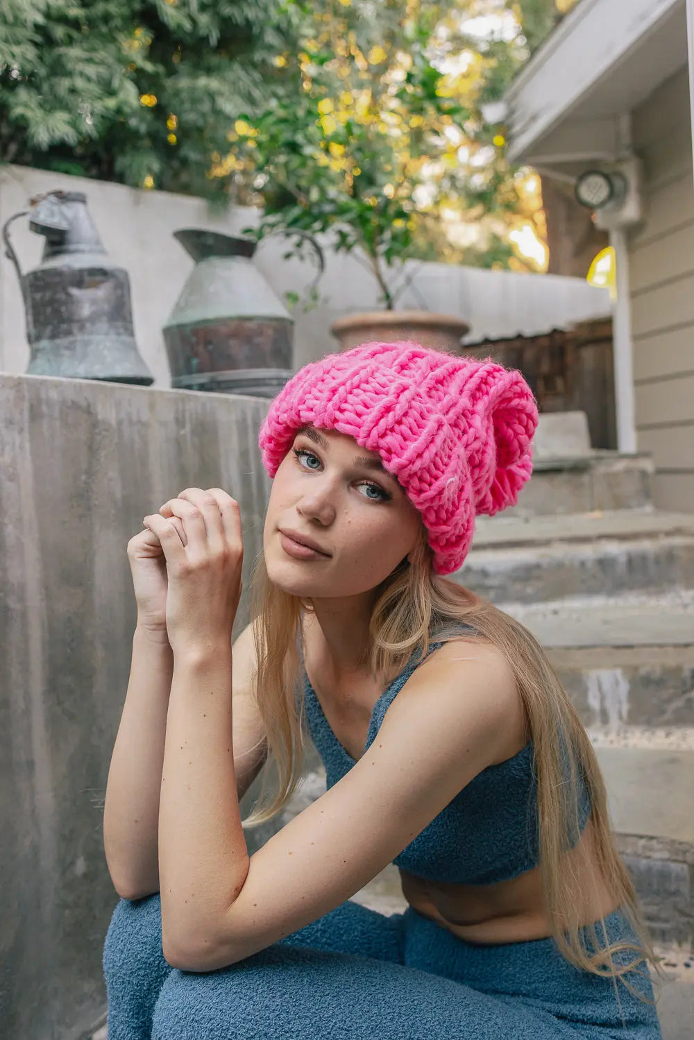 Hot pink cable-knit beanie with chunky stitch pattern and pom-pom