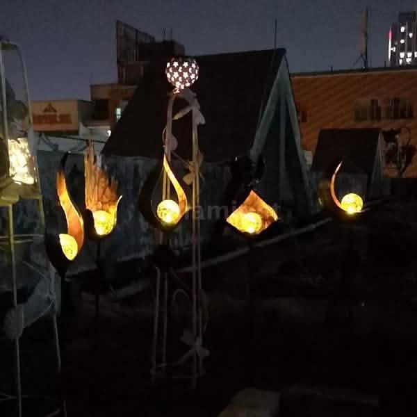 Group of solar LED flame stake lights glowing along a dark outdoor yard