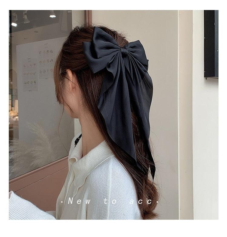 Black satin bow hairpin with long ribbon tails on long hair