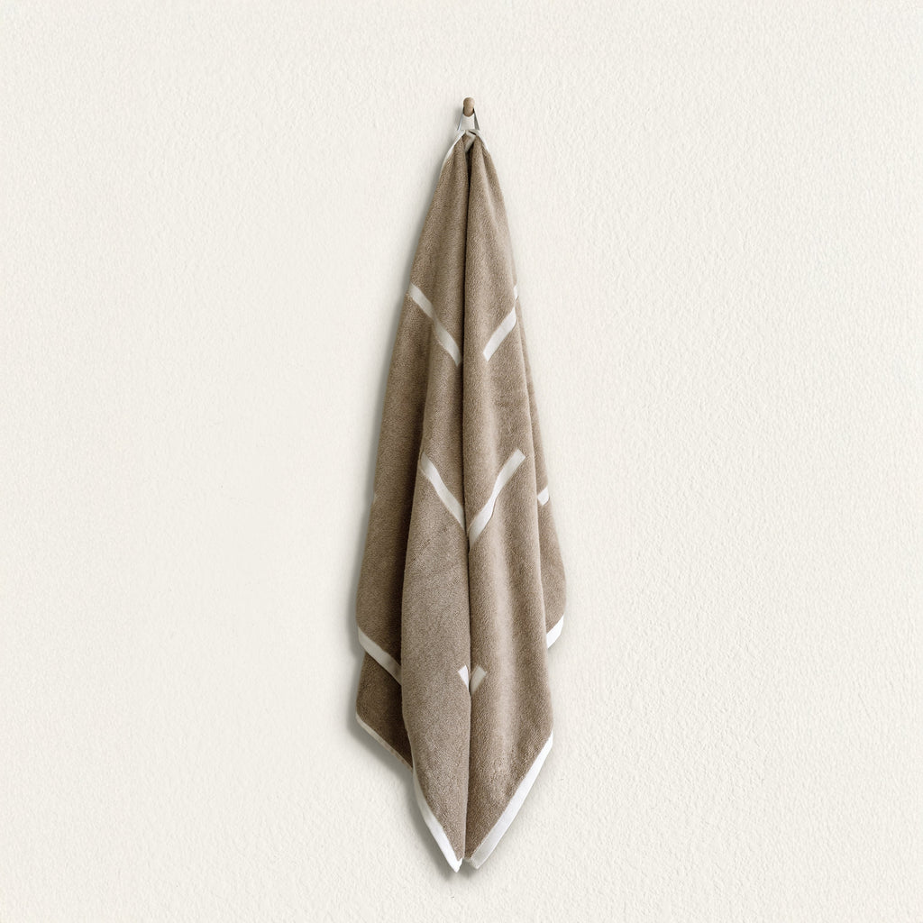 Tan cotton towel with geometric ecru stripe pattern, hanging
