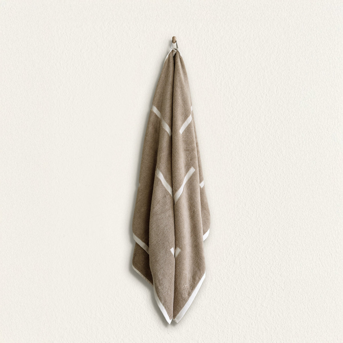 Tan cotton towel with geometric ecru stripe pattern, hanging