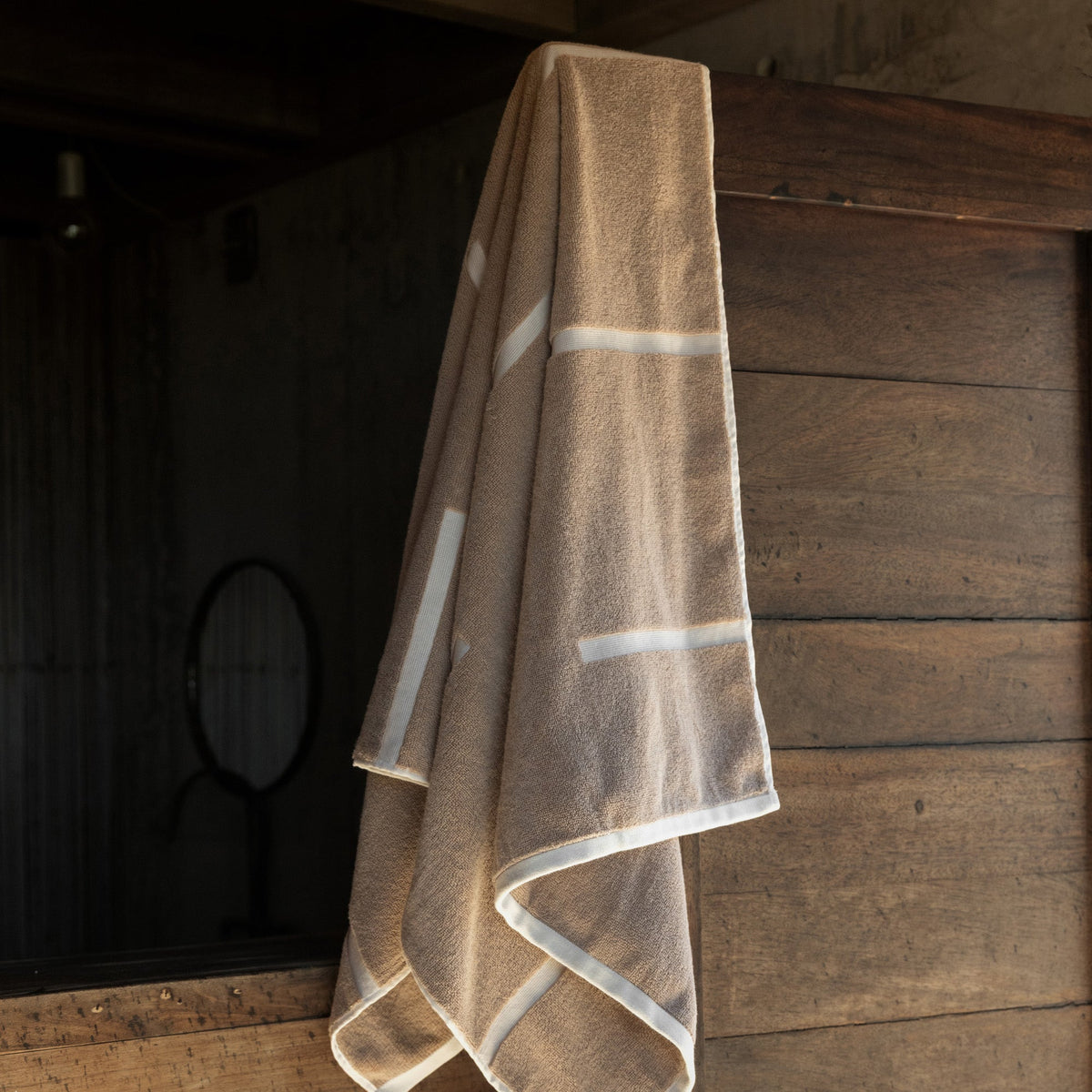Tan and ecru cotton bath towel with bold stripe bands and stitched edging.