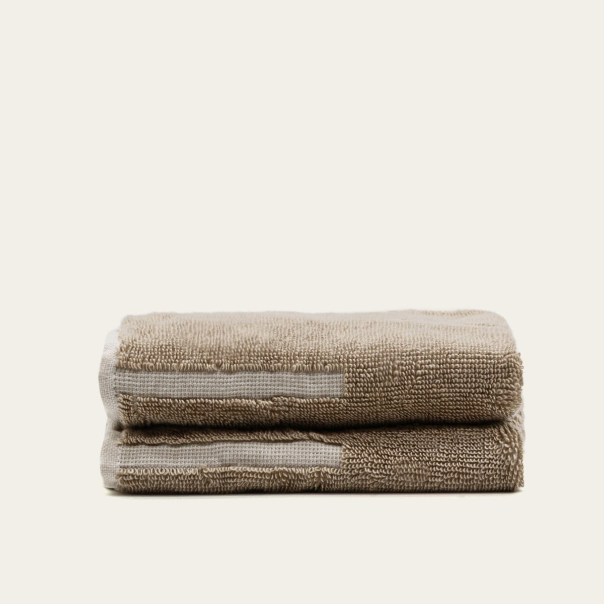 Folded tan cotton towel with ecru stripe accent, thick textured loop pile.
