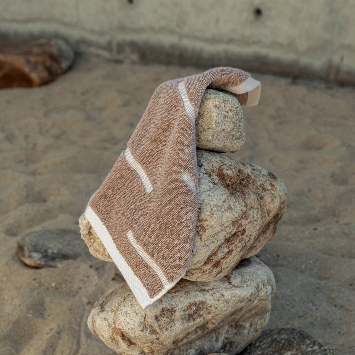 Tan cotton washcloth with ecru striped border, folded and ready to use
