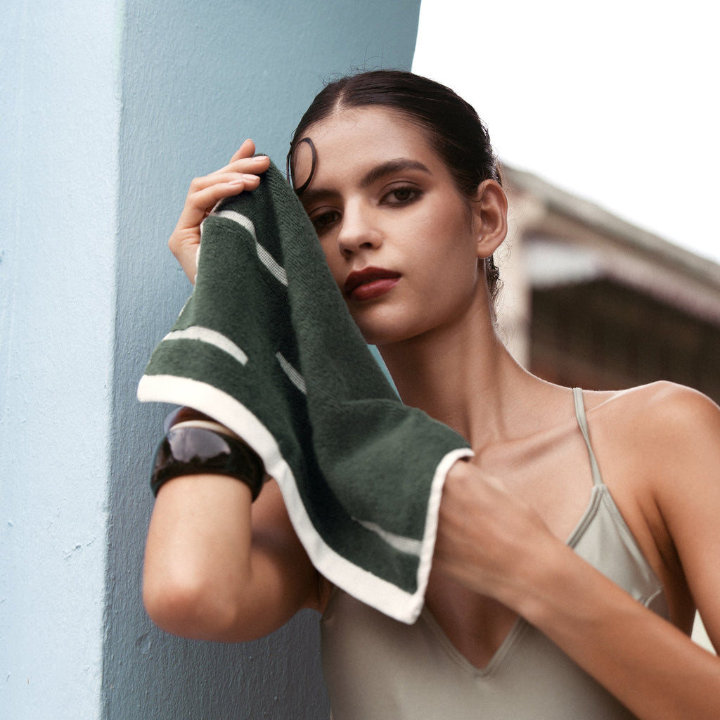Australian cotton towel in dark green with cream-white striped border, draped over shoulder