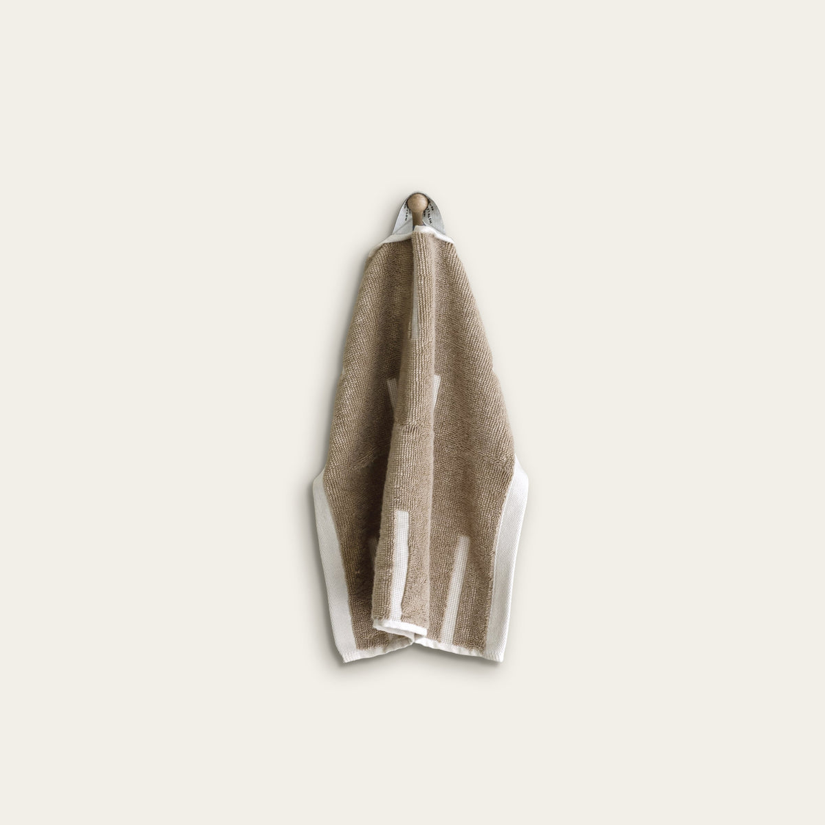 Tan cotton washcloth with ecru border stripes, neatly folded with hanging loop