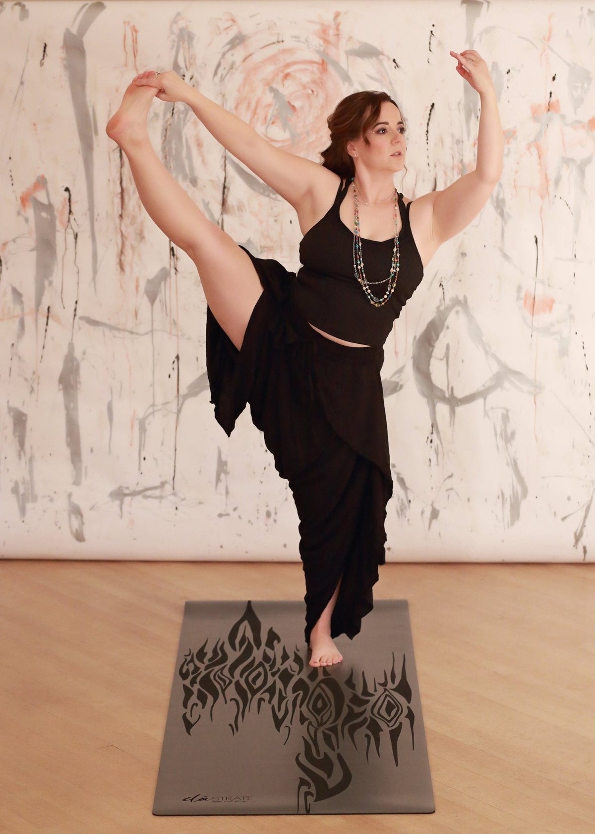Gray yoga mat with a black flame-like design under a standing yoga pose