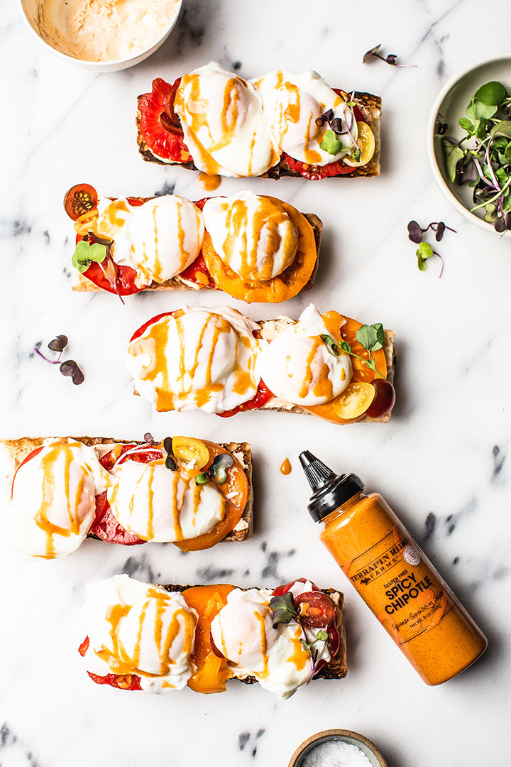 Spicy chipotle squeeze bottle with drizzled sandwiches and green garnish