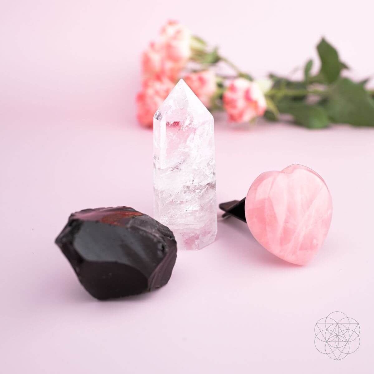 Crystal set on pink background: rose quartz heart, clear point, and black crystal cluster