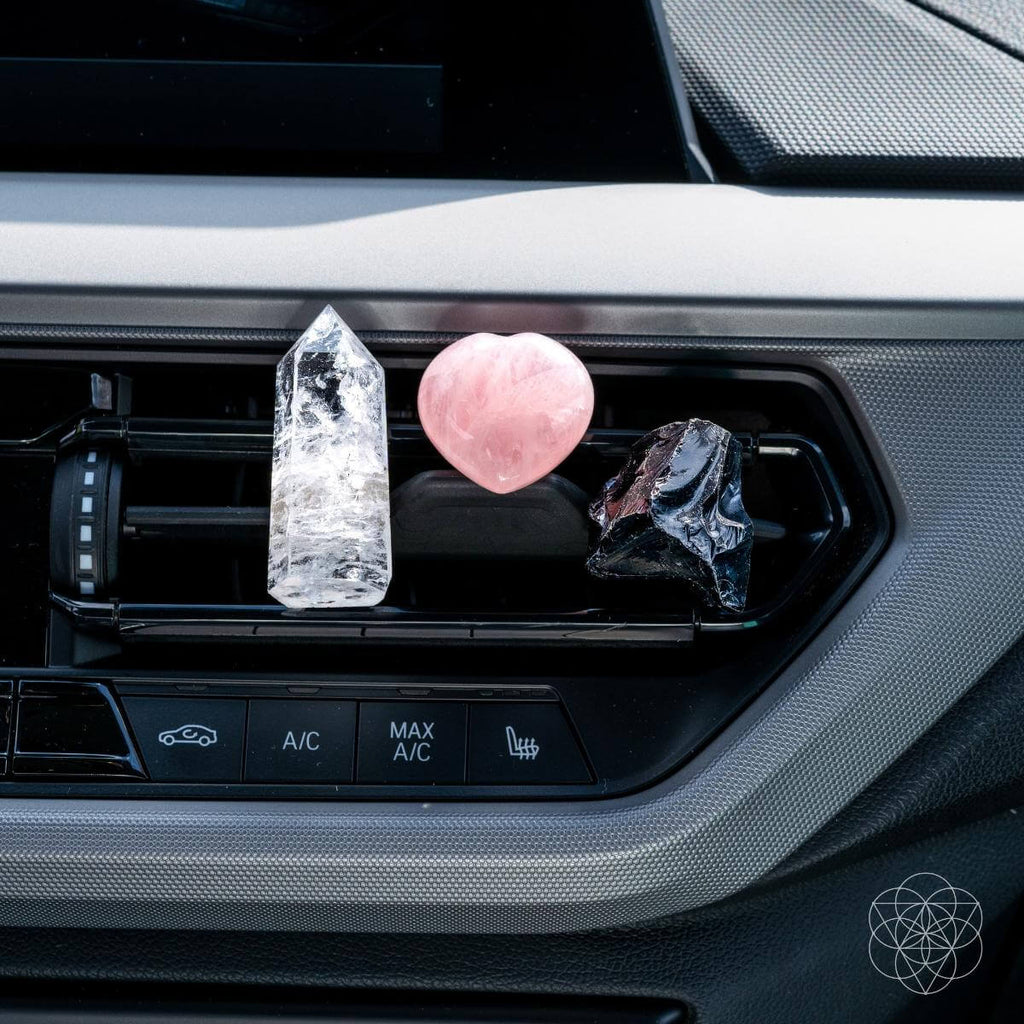 Car dashboard display of crystal kit with rose quartz heart, clear tower, and black crystal