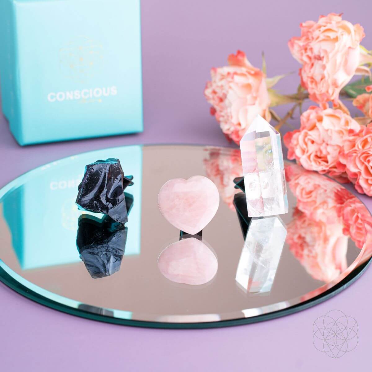 Glass tray display of car crystal kit: rose quartz hearts, clear points, and black pieces
