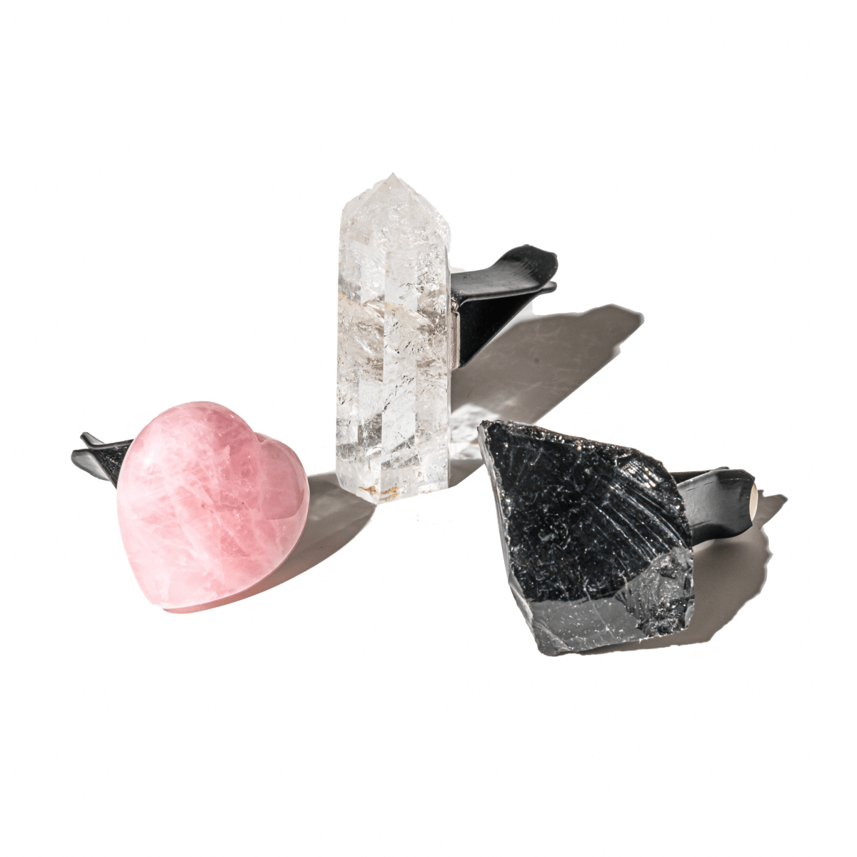 Assorted car crystal pieces: rose quartz heart, clear quartz tower, and dark black crystals