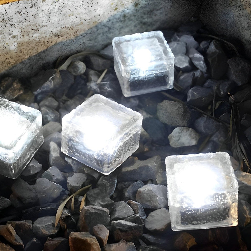 Solar LED ice brick lights glowing white, square translucent bricks on dark gravel