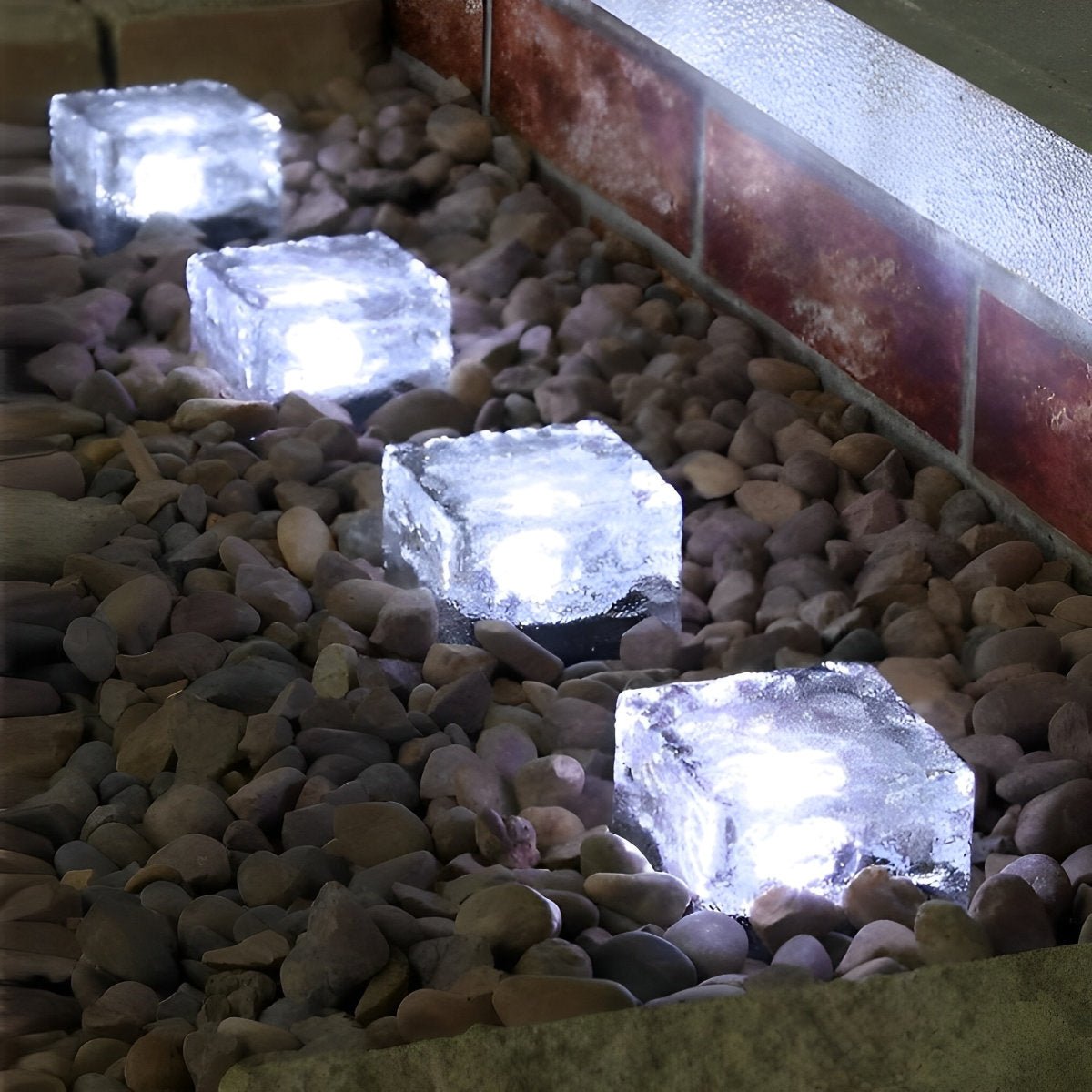 Solar LED ice brick lights emitting cool white glow, square bricks on gravel