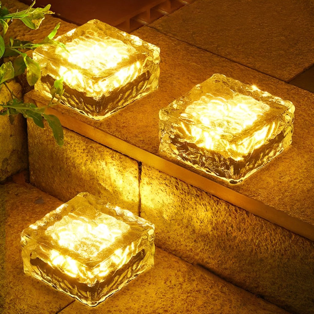 Solar LED ice brick lights glowing golden yellow, square translucent brick on steps