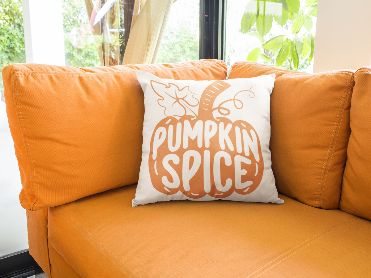 White throw pillow with orange pumpkin spice print on orange couch