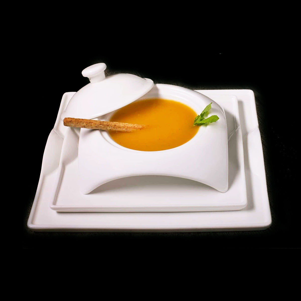 White square porcelain dinner plate with curved rim, holding soup