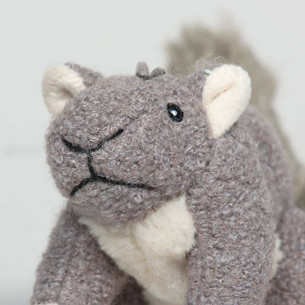 Gray-brown plush squirrel face with black nose, embroidered eyes, and cream muzzle